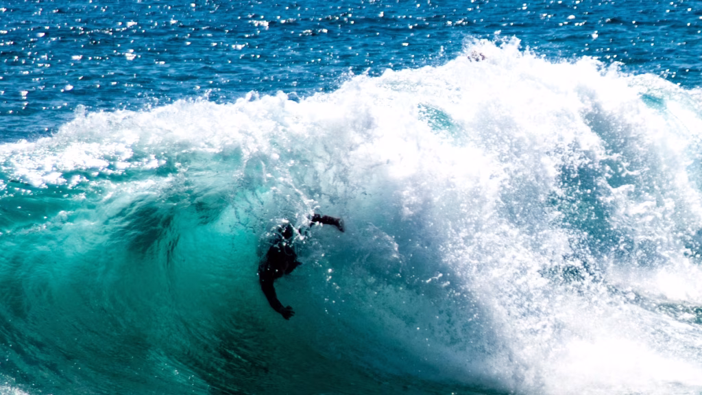 Bodysurfer in a wetsuit riding inside the curl of a breaking wave