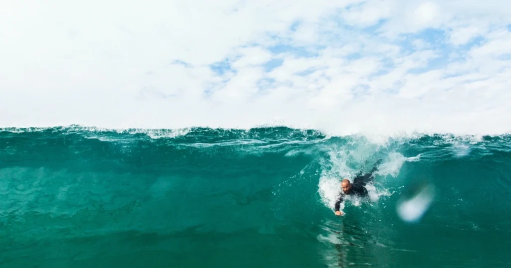 Bodysurfer in a long sleeve surf rash guard riding the face of a green wave