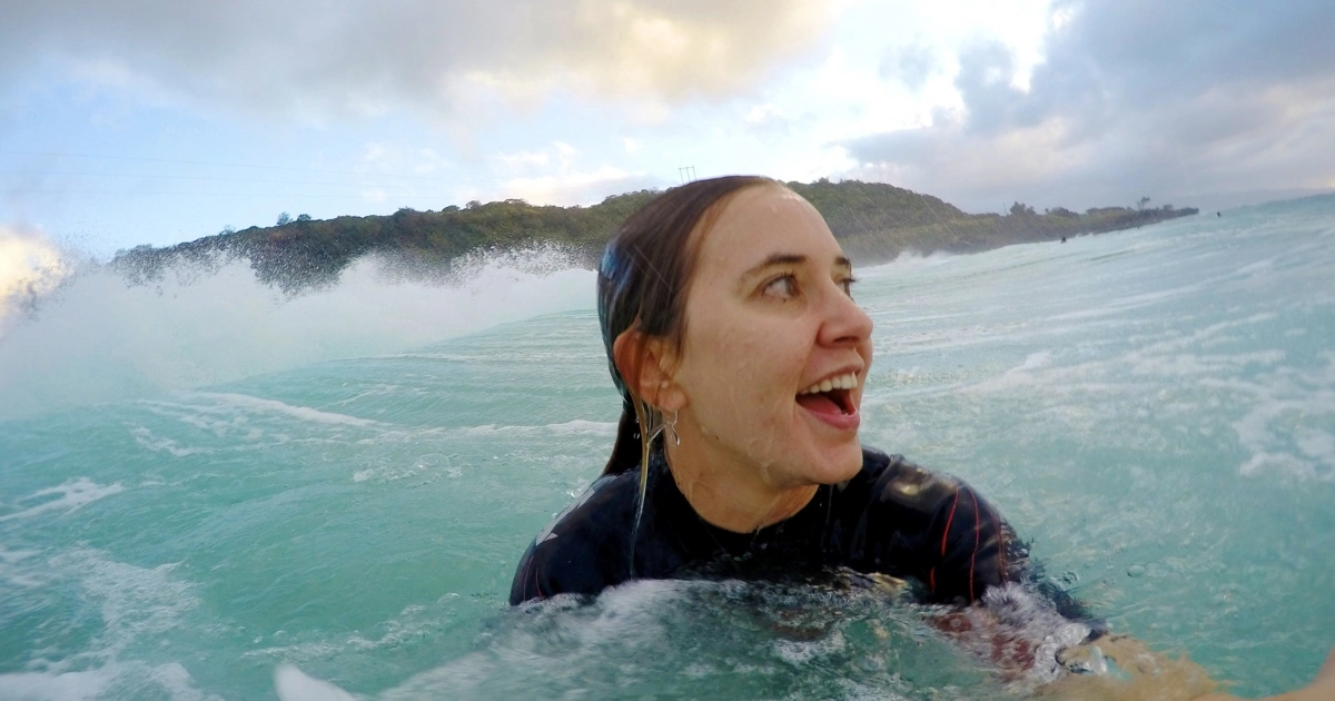 Woman wearing a long sleeve surf rash guard in the whitewater after a wave